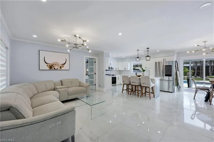Living room featuring suspended lighting, plenty of natural light, and ornamental molding