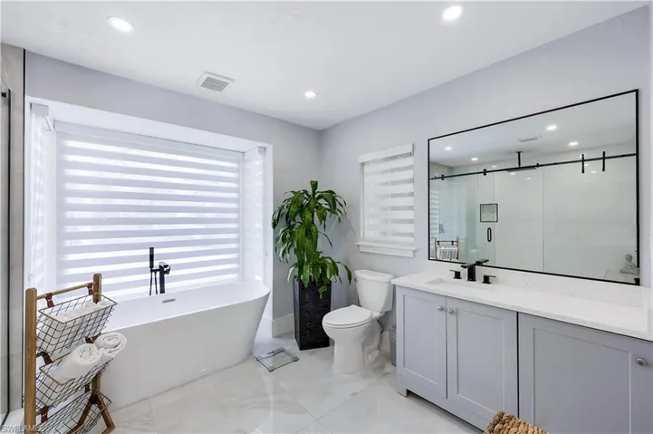 Bathroom with vanity, a stall shower, a freestanding bath, and recessed lighting