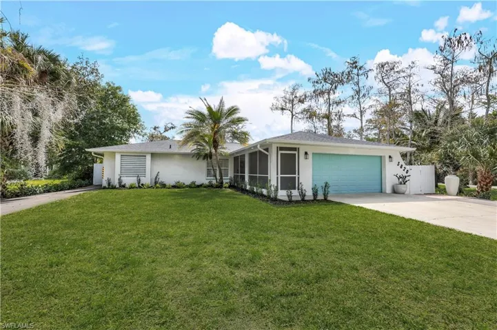 Ranch-style home with stucco siding, a front lawn, driveway, a garage, and a sunroom