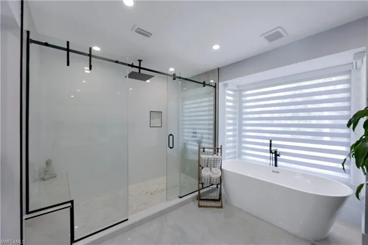 Full bathroom featuring a stall shower, a freestanding tub, and recessed lighting