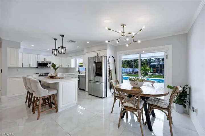 Kitchen with suspended lighting, stainless steel appliances, healthy amount of natural light, a kitchen island, and crown molding