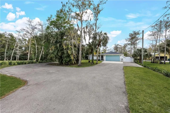 View of front facade featuring driveway, a front yard, and a garage