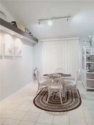 Dining space featuring rail lighting and light tile patterned floors