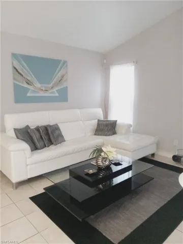 Tiled living area featuring lofted ceiling