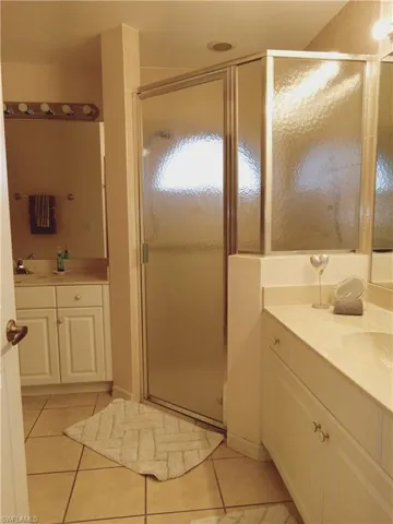 Bathroom with tile patterned flooring, a shower stall, and vanity