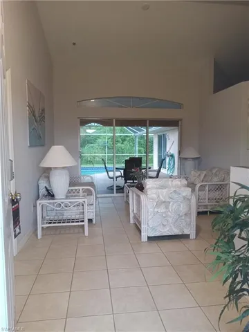 Living area with light tile patterned floors, high vaulted ceiling, and a sunroom