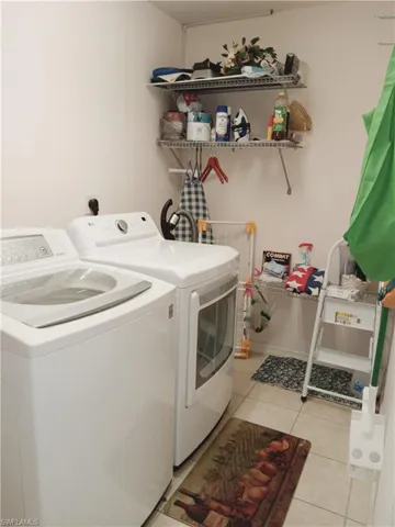 Laundry area with washer and dryer and light tile patterned floors