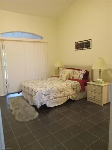 Bedroom with vaulted ceiling and dark tile patterned floors