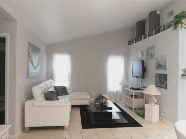 Living area with plenty of natural light, light tile patterned floors, a wood stove, baseboards, and vaulted ceiling