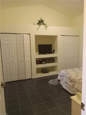 Bedroom featuring dark tile patterned flooring, a closet, and high vaulted ceiling