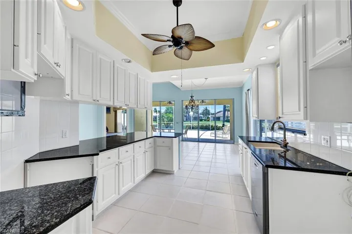Kitchen featuring white cabinetry, dark granite countertops, tile flooring, and recessed lighting