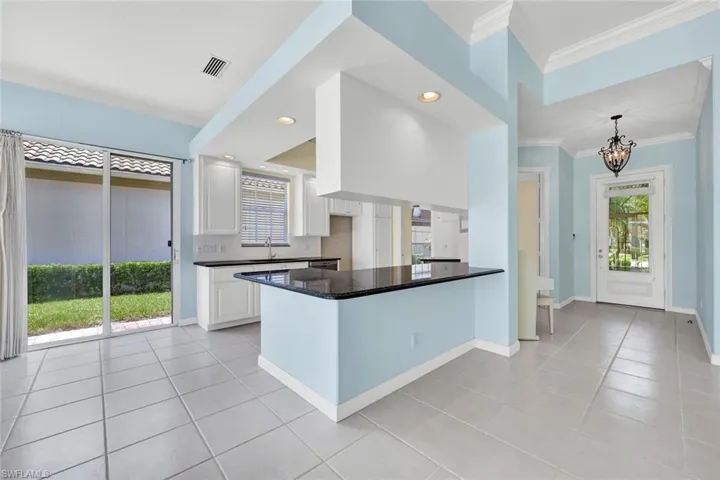 Open-concept kitchen featuring white cabinetry, dark countertops, and a central island with bar seating