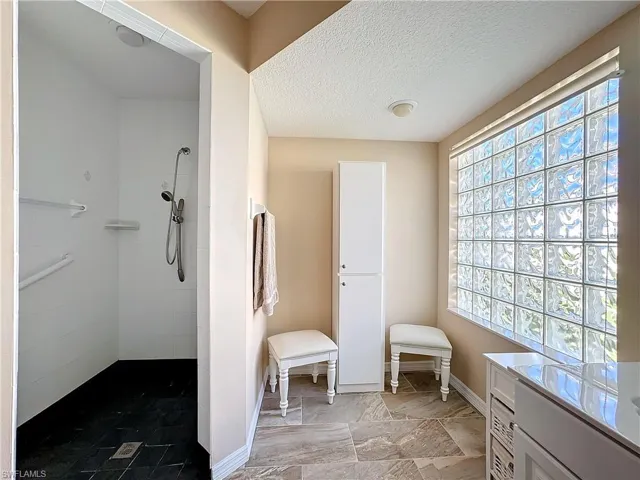 Bathroom featuring tile floors, a textured ceiling, plenty of natural light, and a tile shower