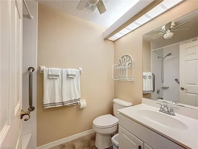 Bathroom featuring toilet, ceiling fan, a textured ceiling, and large vanity