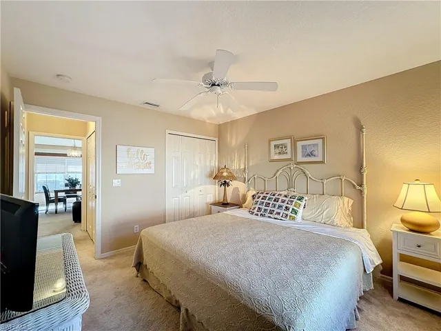 Bedroom with ceiling fan, a closet, and light colored carpet