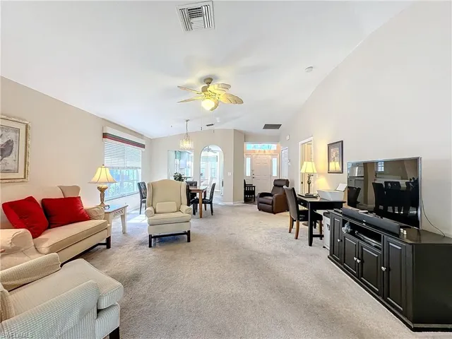 Carpeted living room with vaulted ceiling and ceiling fan