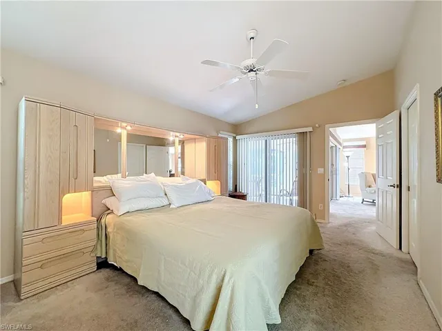 Carpeted bedroom with ceiling fan and lofted ceiling
