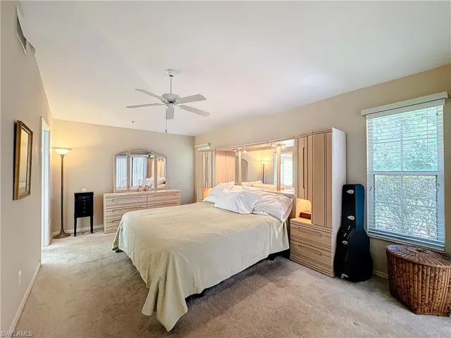 Carpeted bedroom with ceiling fan and multiple windows