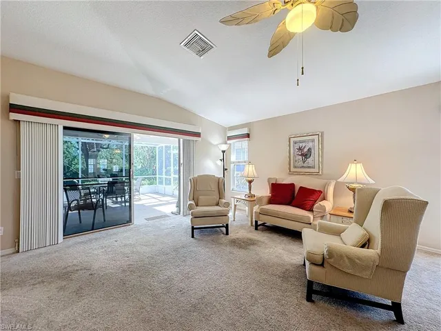 Living room featuring ceiling fan, carpet floors, a textured ceiling, and vaulted ceiling