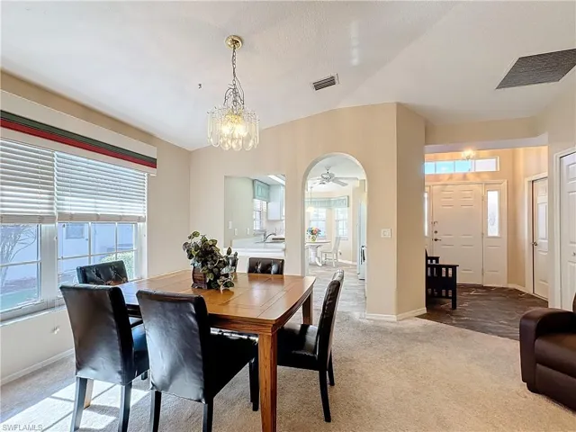 Carpeted dining space featuring sink and ceiling fan with notable chandelier