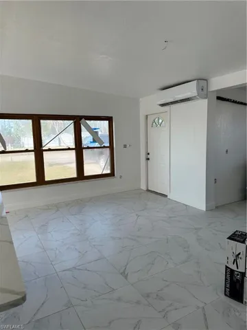 Unfurnished living room with baseboards and light marble finish flooring