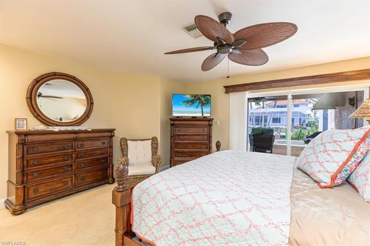 Sliding glass doors, outdoor patio, ceiling fan, carpet flooring, and neutral wall paint