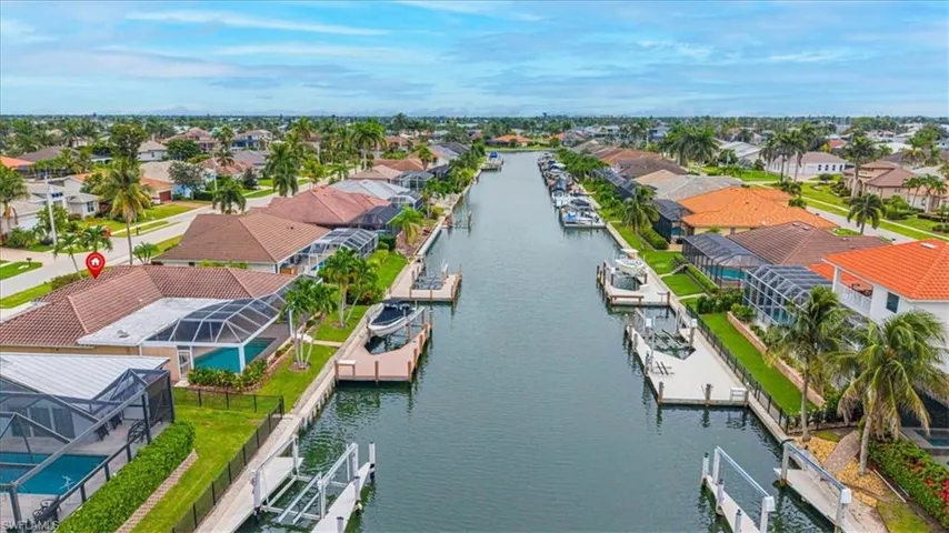 Canal-front property featuring a private dock, screened-in swimming pool enclosure, and a tiled roof