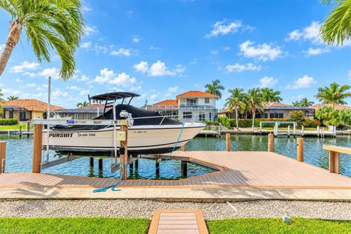 Waterfront property featuring a private boat lift, composite decking, and manicured landscaping
