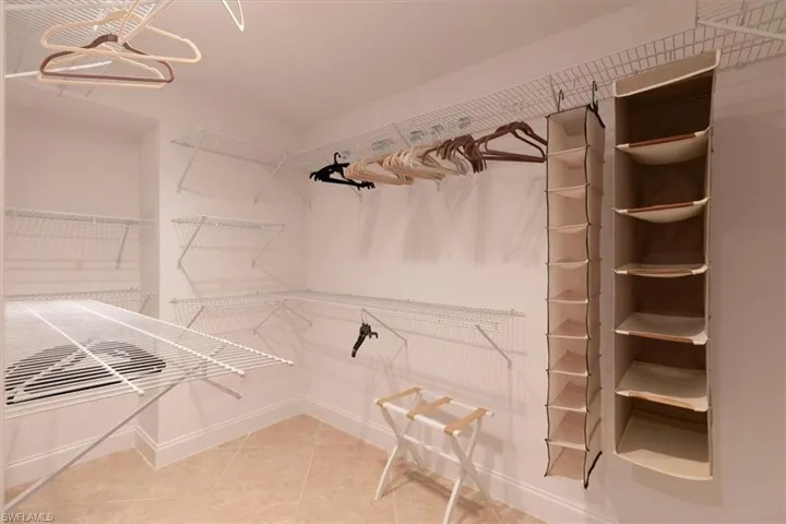 White wire shelving system, integrated hanging rods, and light-toned floor tiles