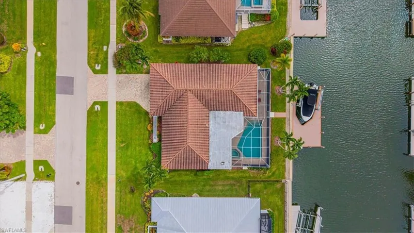 Waterfront property featuring a private boat dock, screened-in swimming pool, and a tiled roof