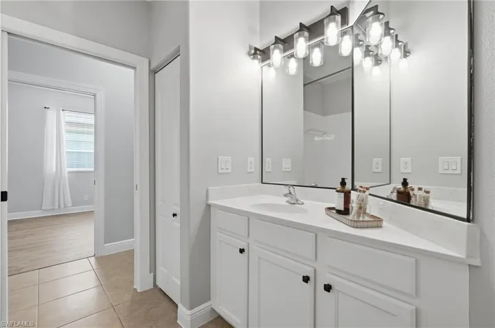 Bathroom vanity featuring a single sink, light countertop, and a wide mirror