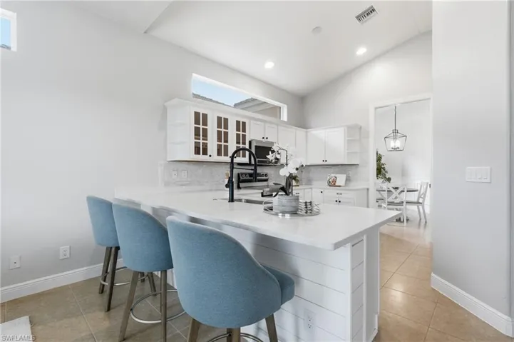 Kitchen featuring a large island with white shiplap paneling, light-toned countertops, and a black gooseneck faucet