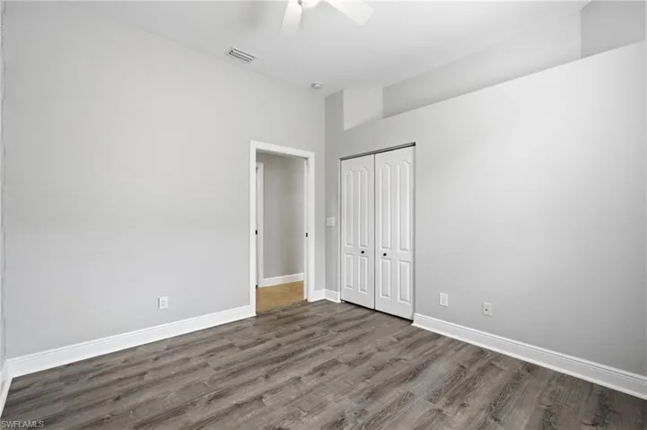 Spacious room featuring wood-finish flooring, vaulted ceilings, and a ceiling fan