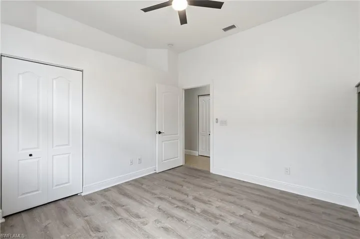 Spacious room featuring light wood-finish flooring, white walls, and a ceiling fan
