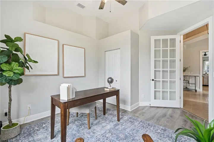 Interior space featuring a French door entry, vaulted ceiling, wood-finish flooring, and white baseboards