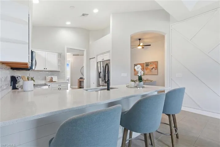 Kitchen island with a light-toned countertop, integrated sink, and matte black faucet