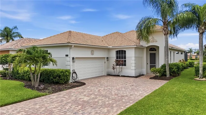 Mediterranean-style residence featuring a stucco exterior, a tiled roof, an arched entry, a two-car garage, and a paver driveway