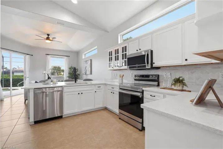 Kitchen featuring white cabinetry, light-toned countertops, stainless steel appliances, and a tiled backsplash