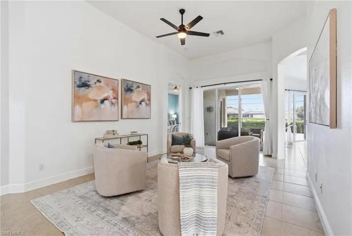 Vaulted ceilings featuring a ceiling fan, tile flooring, and sliding glass doors opening to an outdoor area