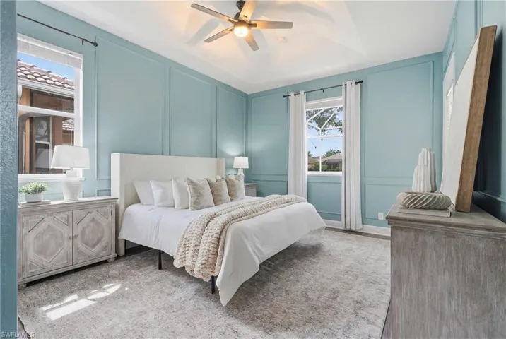 Spacious room featuring elegant wainscoting, tray ceiling, and a ceiling fan
