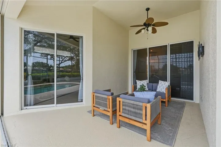 Covered patio featuring a ceiling fan, textured concrete flooring, and multiple sliding glass doors