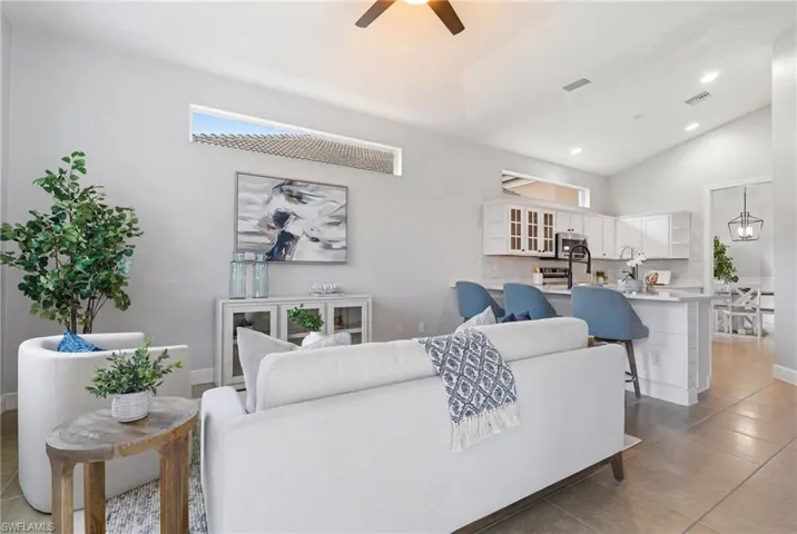 Light-filled living space featuring a vaulted ceiling and tile flooring
