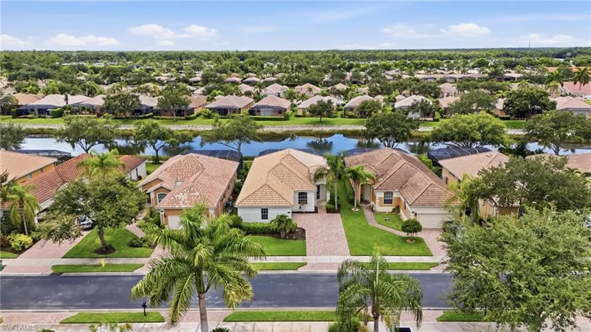 Aerial perspective showcasing a residential community with numerous homes featuring tile roofs and lush green landscaping