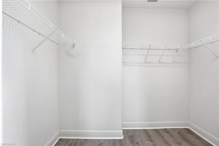 Walk-in closet featuring light wood-finish flooring, white wire shelving, and crisp white walls with matching baseboards