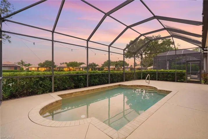 Screened-in outdoor pool area featuring a rectangular pool with an integrated curved spa, brick coping, and a concrete deck