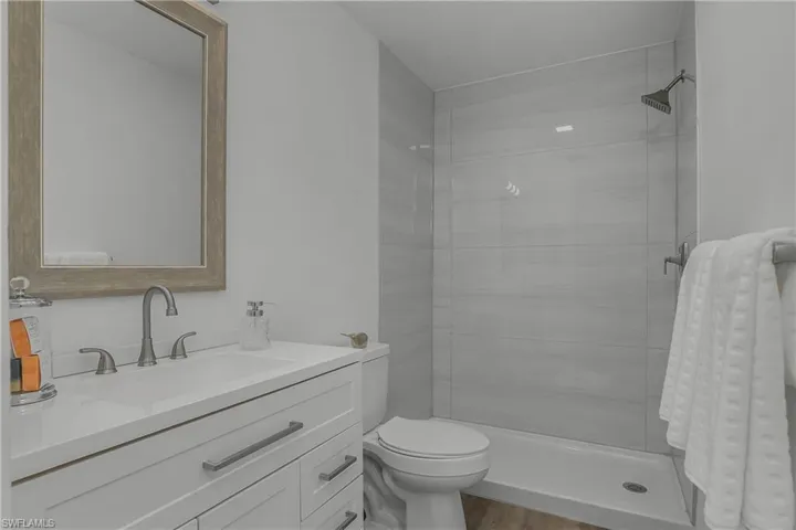 Stunning REMODELED bathroom has a walk-in shower, new tile, vanity, countertops, lighting, mirror, toilet, laminate flooring, trim and hardware.