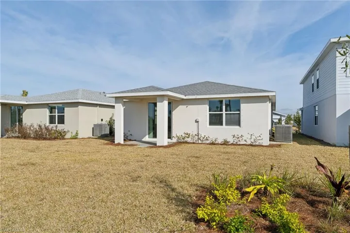 Rear view of property featuring central AC unit and a lawn