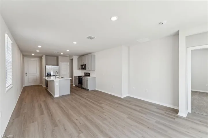 Unfurnished living room featuring plenty of natural light, sink, and light wood-type flooring