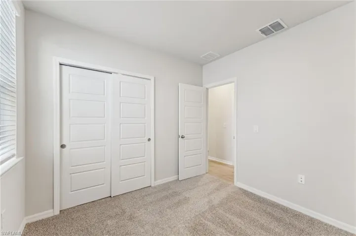 Unfurnished bedroom with light colored carpet and a closet