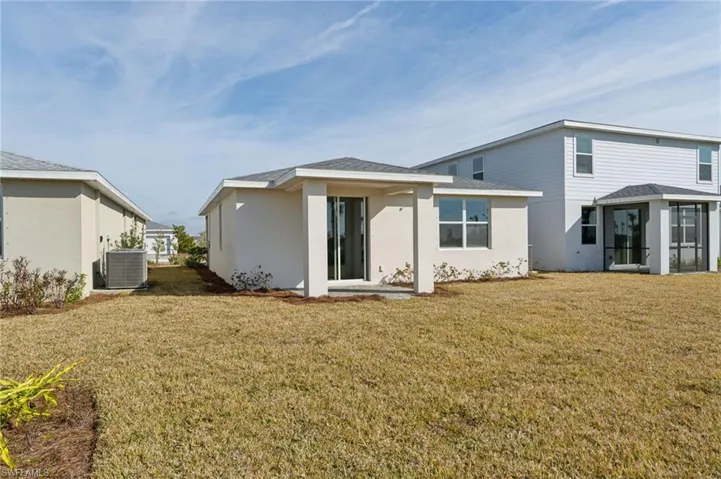 Rear view of property featuring central AC unit and a yard